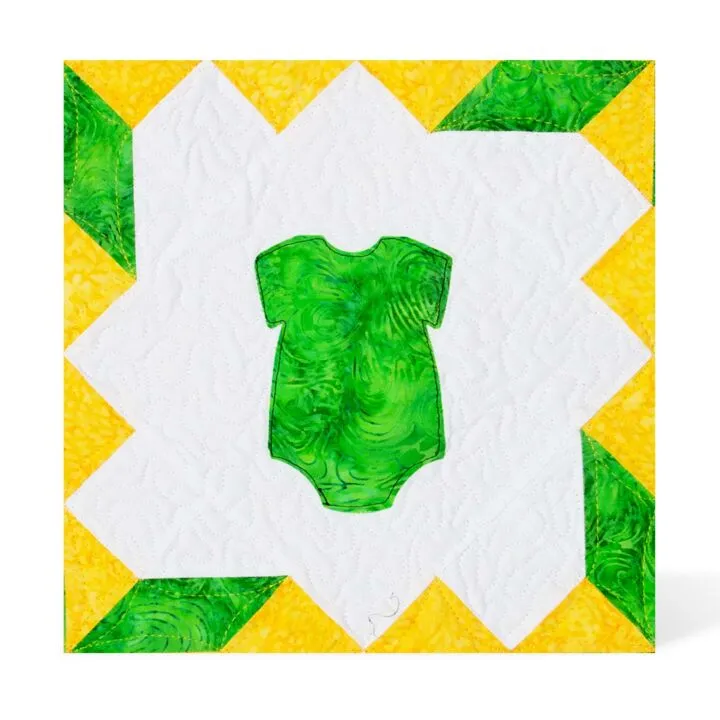 Green onesie applique on a quilted yellow and white background design.